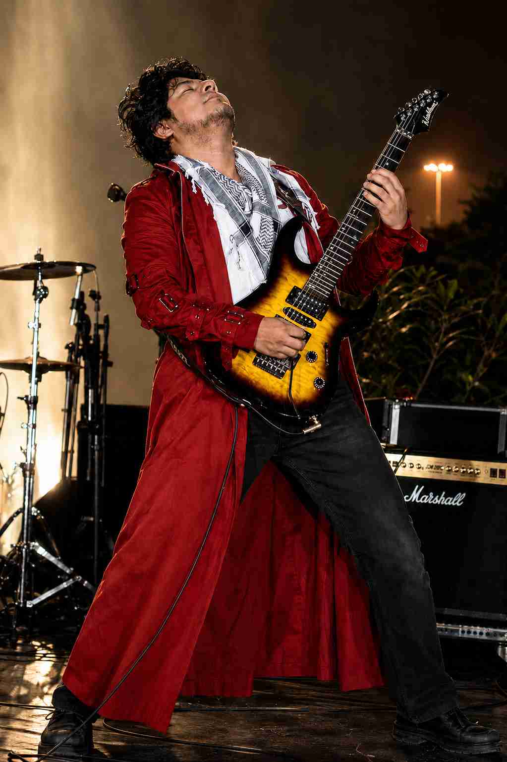 Val Staccato Peruvian instrumental rock guitarist performing live wearing red coat playing Washburn electric guitar on stage