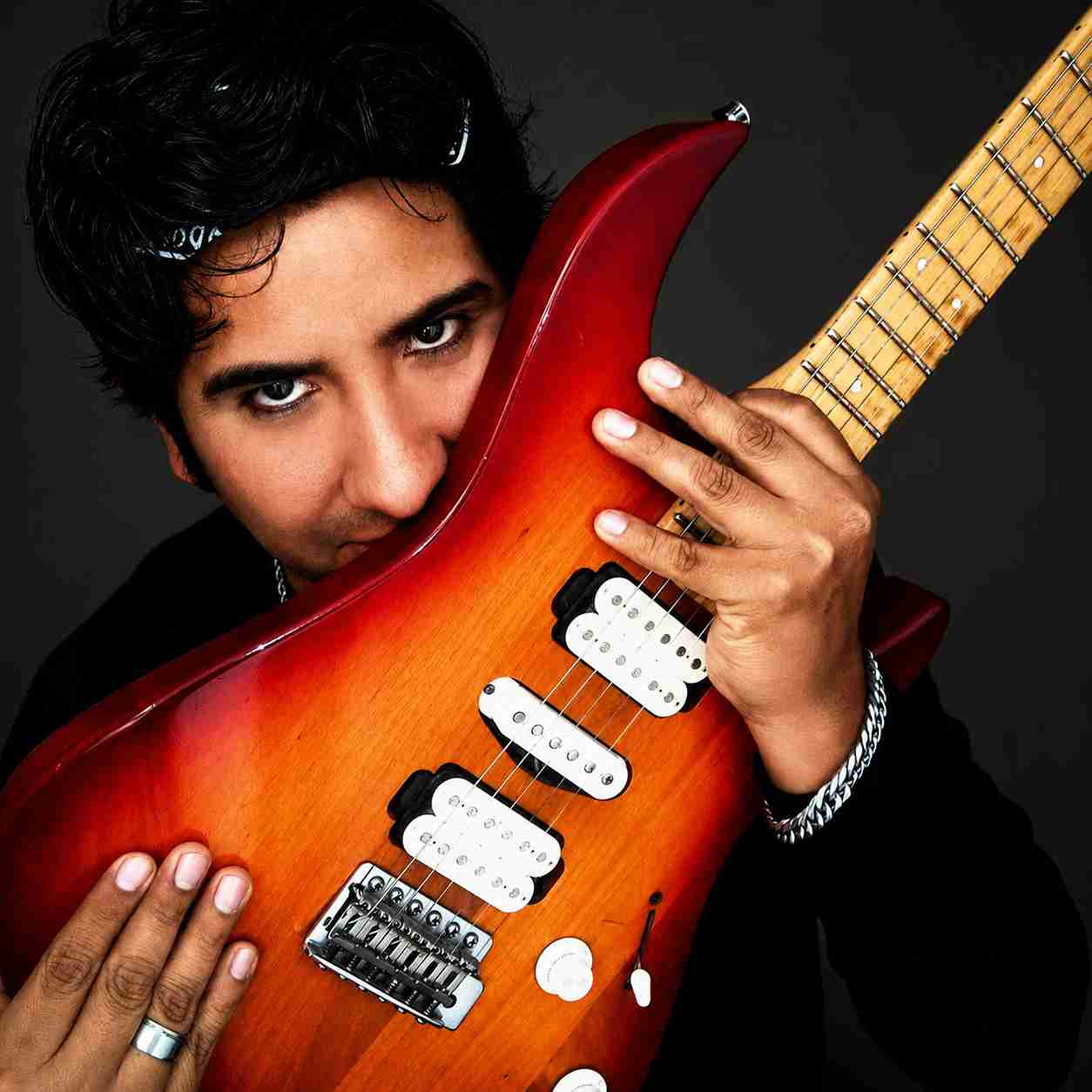 Val Staccato Peruvian instrumental rock guitarist closeup portrait holding red electric guitar face intense expression