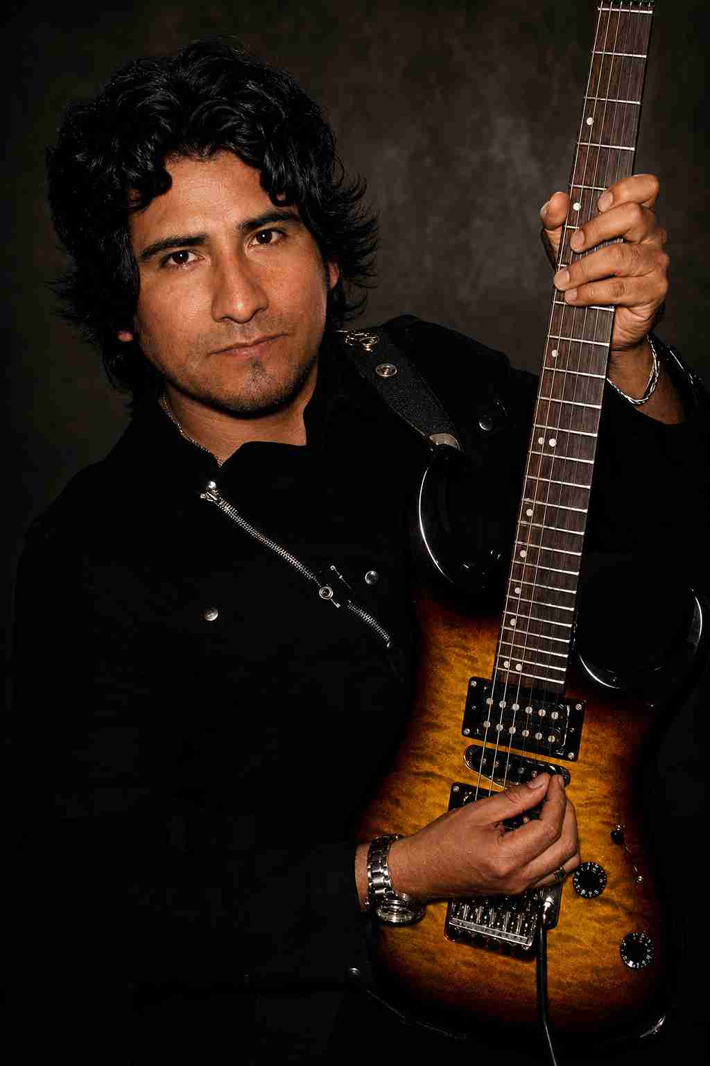 Val Staccato Peruvian instrumental rock guitarist official portrait black outfit holding Washburn sunburst electric guitar