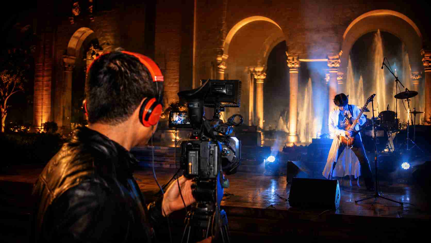 Val Staccato live concert performance being filmed professionally on stage with Roman arches blue light Lima Peru instrumental rock guitarist